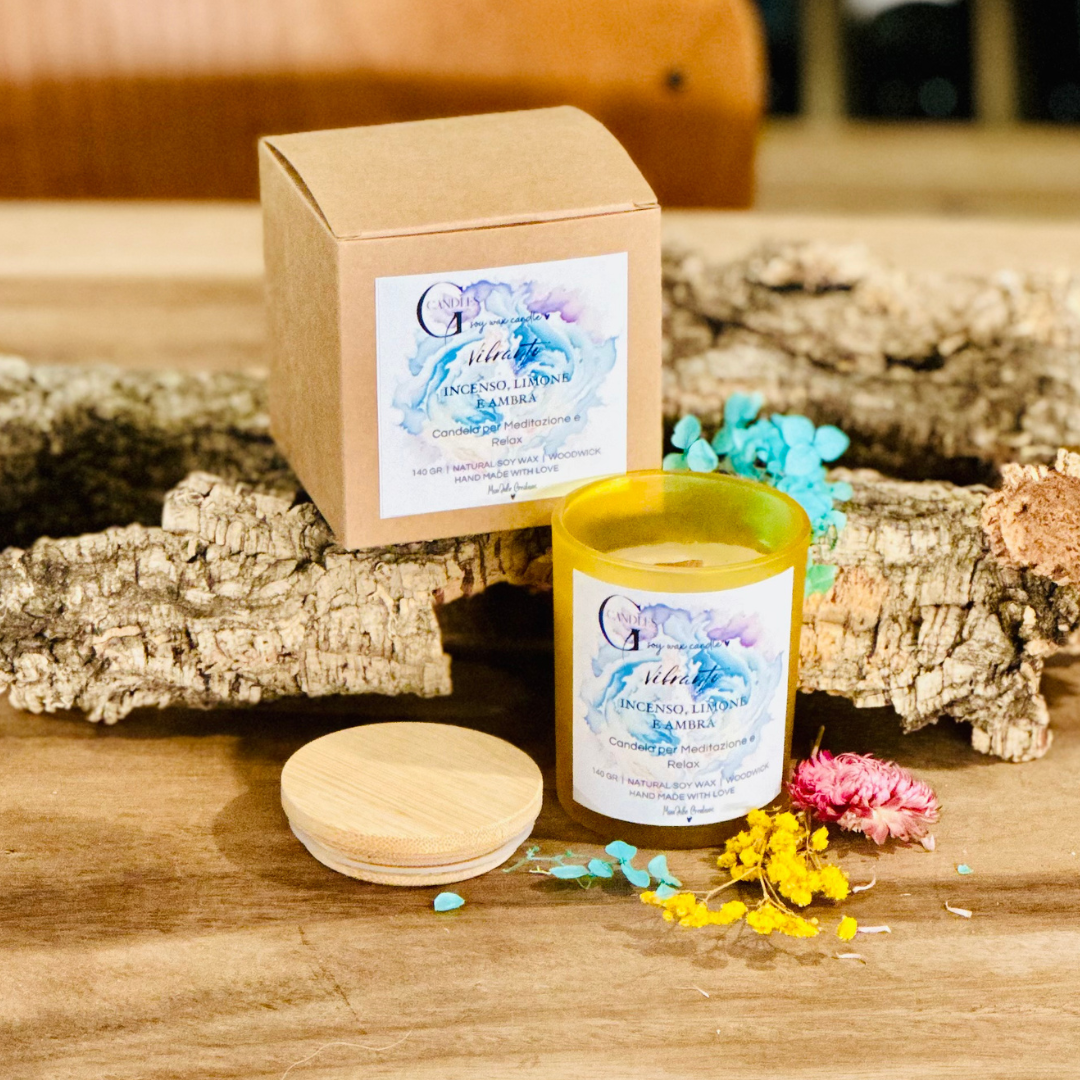 Vasetto giallo in vetro con coperchio in bambu' per candela da meditazione alla cera di soia artigianale al profumo di franchincenso, limone e ambra, la grafica è realizzata su sfondo viola, blu e giallo chiaro.