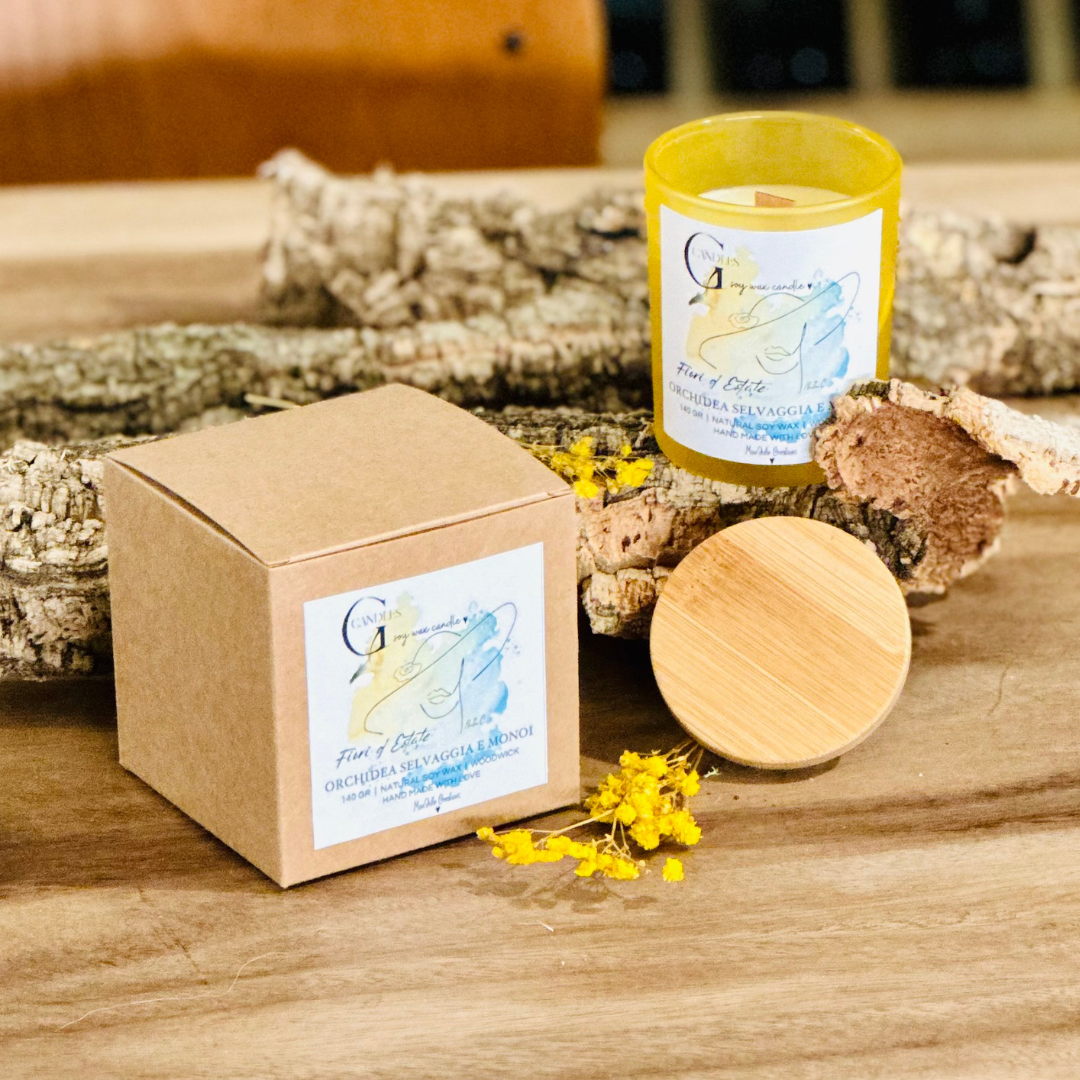 Vasetto giallo in vetro con coperchio in bambu' per candela alla cera di soia artigianale profumata al Monoi, la grafica realizzata a mano rappresenta un volto di donna stilizzato su sfondo giallo e blu.