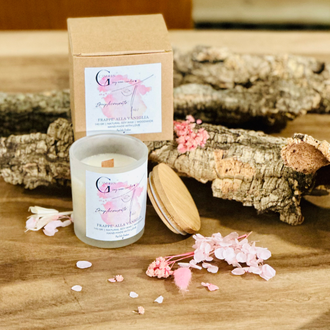 Vasetto in vetro satinato con coperchio in bambu' per candela alla cera di soia artigianale profumata al frappè alla vaniglia, la grafica realizzata a mano rappresenta un volto di donna stilizzato su sfondo rosa.