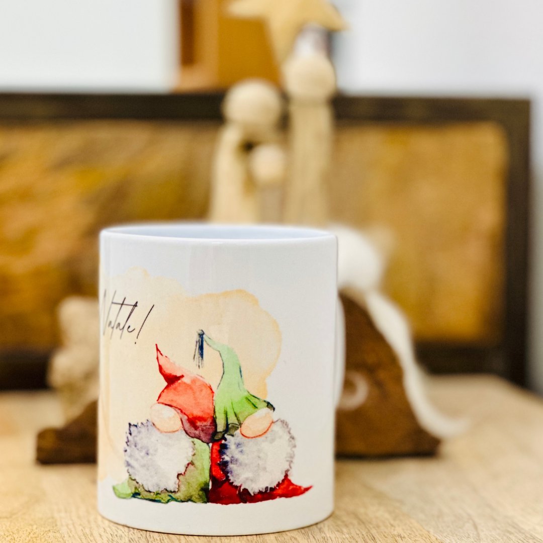 Tazza mug originale natalizia, con stampa e progetto grafico realzzati a mano. due simpatici gnomi rossi e verdi augurano Buon Natale con la scriita impressa sulla tazza. 