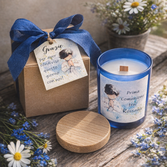 Bomboniera candela profumata in vasetto di vetro blu con stoppino in legno. Grafica artigianale e personalizzata, scatolina kraft con fiocco blu. Fiorellini azzurri e margherite bianche come elementi decorativi su piano in legno rustico.