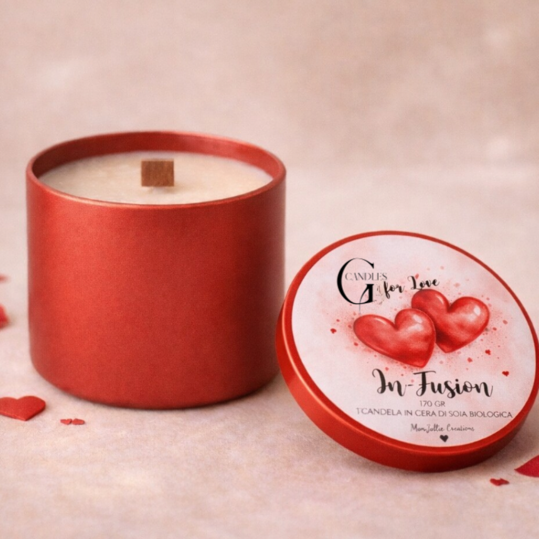 Candela in cera di soia bianca al profuma per San Valentino "In-Fusion" con stoppino in legno in barattolino rosso. Grafica artigianale su coperchio. Piano in legno chiaro e petali rossi come dettagli decorativi.