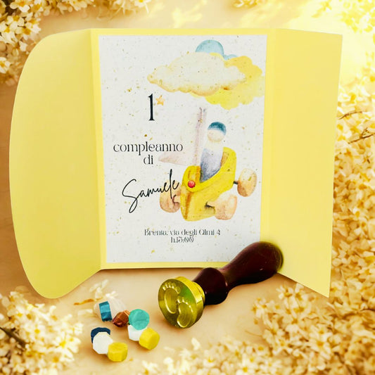 Invito primo compleanno bimbo personalizzato, doppio cartoncino giallo chiaro, con sigillo in ceralacca e fiorellini bianchi.