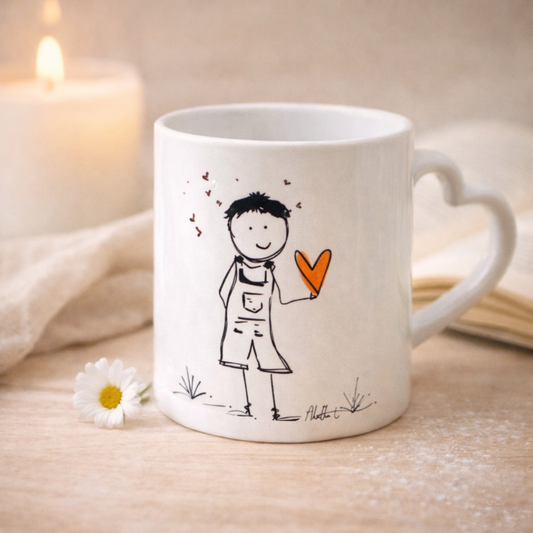 Tazza mug in ceramica bianca con manico a cuore per San Valentino, grafica realizzata a mano reffigurante un maschietto stilizzato che tiene in mano un cuore rosso. Sfondo chiaro e delicato, candela, margherita e  tovagliolo in lino naturale come elementi decorativi.
