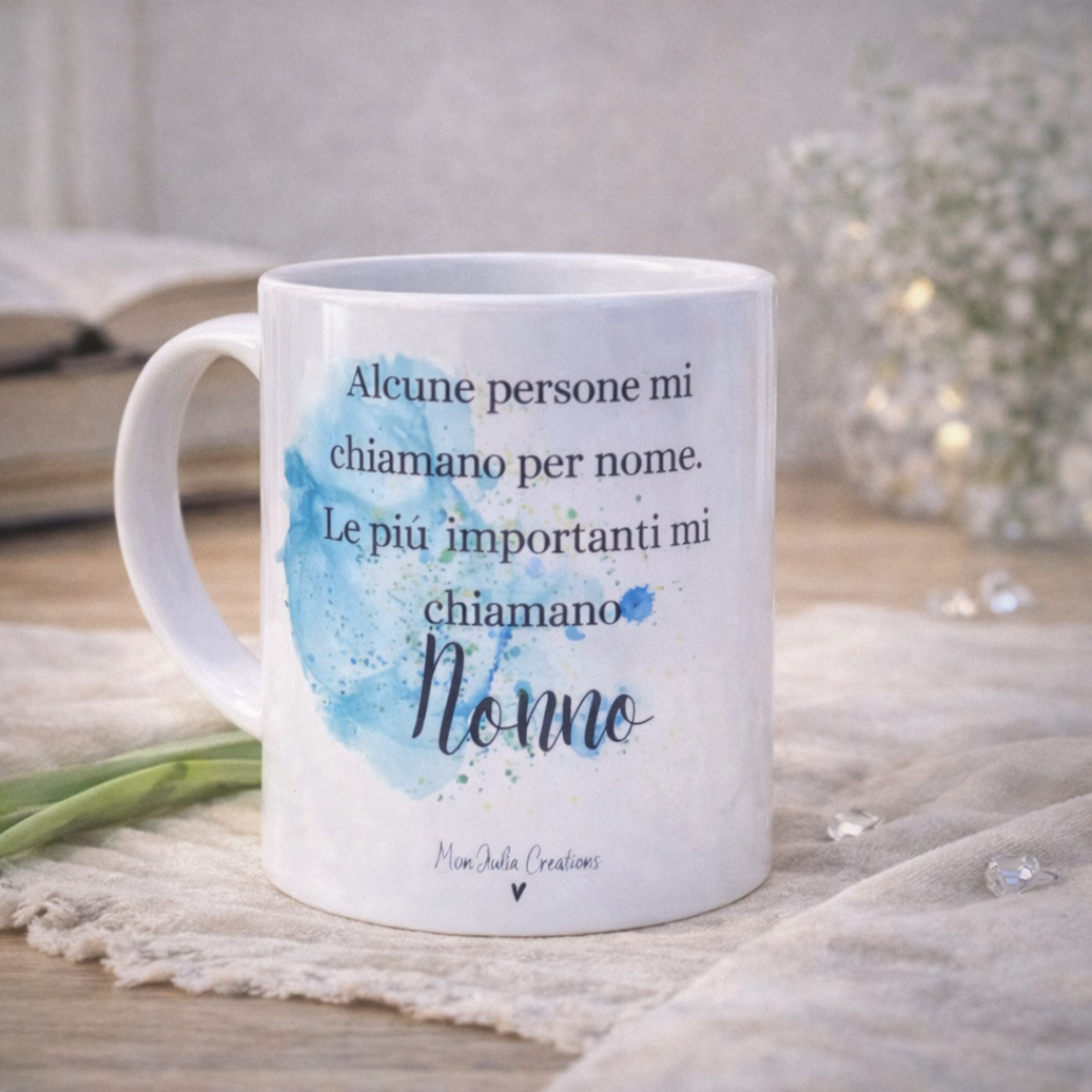 Tazza in ceramica bianca con dedica per il nonno con sfumatura acquerello blu, su piano in legno chiaro, su tessuto in lino naturale e dettagli decorativi.