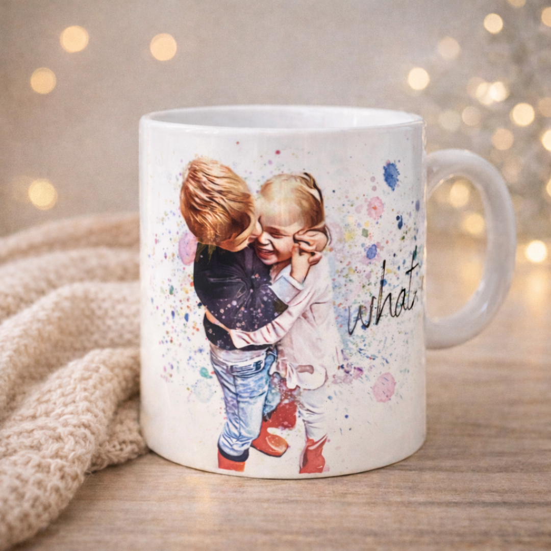 Tazza mug in ceramica bianca realizzata a mano, raffigurante due bimbi che si abbracciano scherzosamente, in versione pastello con frase dedicata, su piano in legno chiaro,  copertina e lucine sullo sfondo.