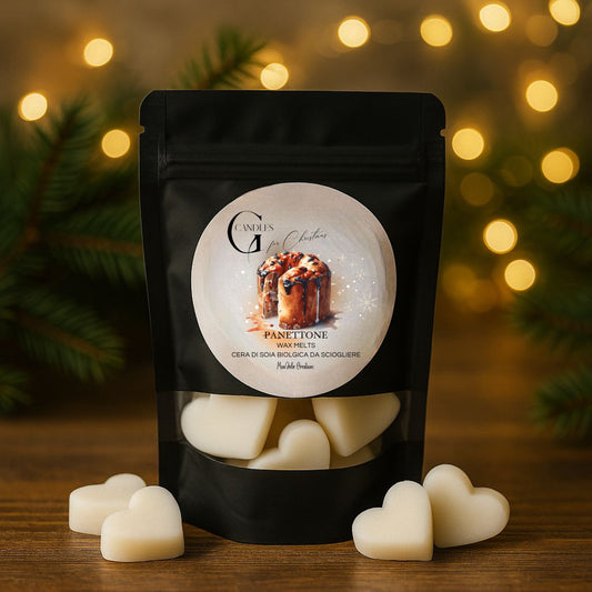Wax melts natalizie al profumo di panettone, artigianali in cera di soia biologica a forma di cuoricini, in bustina nera con finestra trasparente.  Sfondo con atmosfera natalizia con rami di abete, lucine e piano in legno rustico.